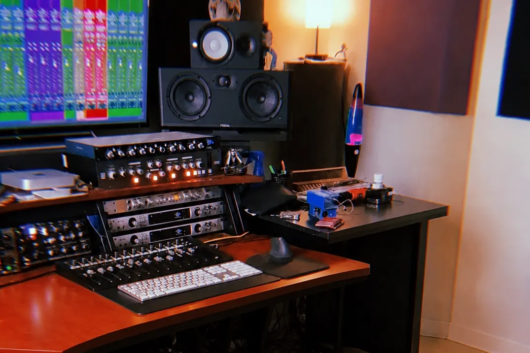 Sala de control: monitores, convertidores y equipo analógico en el escritorio.
